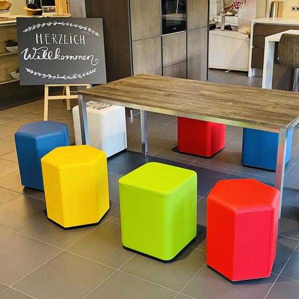 Bunte Hocker stehen um einen Tisch.